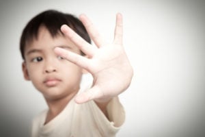 A child raises its hand, seeming to protect theirselves.