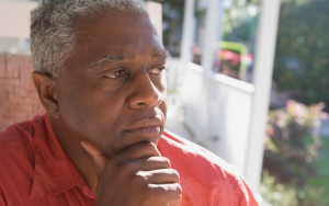 Older man looking thoughtfully, contemplatively into the distance from his porch