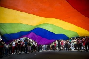 A group of activists rallying under a rainbow flag