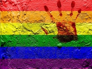 LGBQ pride flag painted on a wall with a handprint in the top righthand corner