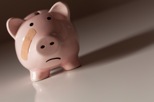 A piggy bank with a sad face and a bandaid on its face