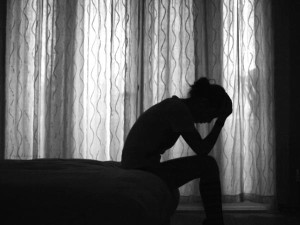 Silhoutte of a sad person sitting on a bed