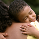 A child hugging an adult, looking happy