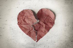 A red heart crumpled up on paper is torn in half