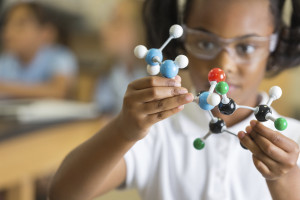 A young child is playing with a molecular model in a science class