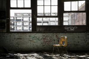 A plastic chair sits in the window light of an abandoned school in Chicago