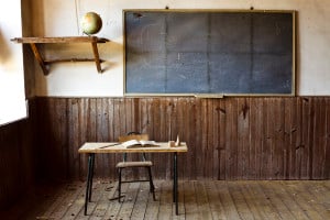 An old classroom is shown with an empty desk