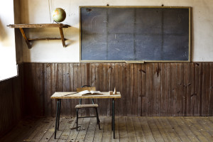 An old classroom is shown with an empty desk