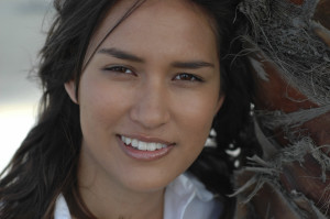 Young person leaning against a palm tree, smiling