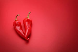 Two chili peppers against a red background