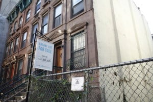 Next to brownstones, a vacant lot is for sale in Harlem
