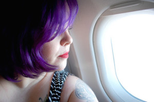 An image of the author, Jes Baker, looking out a plane window