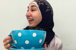 The author, looking away, holding a large, blue, polka-dotted teacup