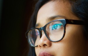 Closeup on a person's face. They have dark-rimmed glasses and they stare off to the left.