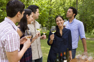 A group of young people drinking white wine together outdoors.