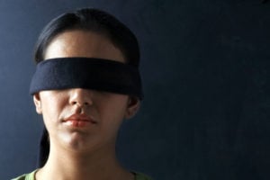 A person from the neck up, facing straight ahead with a blindfold on.