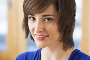 Closeup on a person with short hair who is smiling.