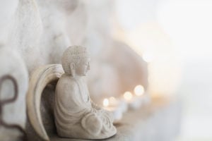 Buddha figurine and candles resting on a ledge.