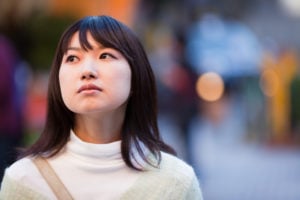 A person who appears to be sad, looking up, standing outside.
