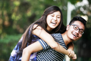 Two young people smiling as one gives a piggyback ride to the other.