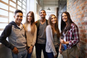 A group of young people standing in a hallway together, smiling.