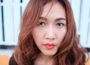 Closeup of a person with bright red lipstick gazing into the camera.