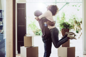 A person happily lifting another person, surrounded by moving boxes.