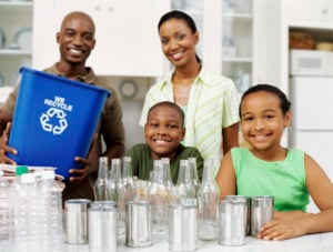 A smiling family of four pose with their recycling.