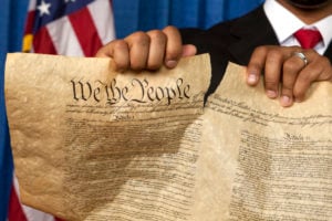 Hands tear up the Constitution in protest.