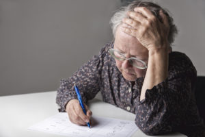 An elderly person struggles to learn how to write.