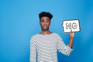 A person stands in front of a blue background, holding up a speech bubble with the word "NO." Image courtesy of Thinkstock; text added by EF.