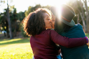 Two people kissing in a park