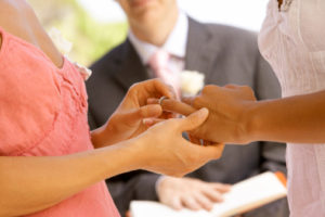 One person putting a ring on another person's hand during a wedding ceremony