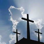 Three crosses in silhouette against a blue sky.