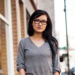 Person standing on a sidewalk, looking ahead seriously