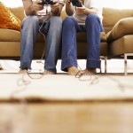 Two people sitting on a couch, playing video games