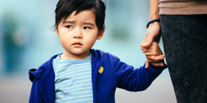 Toddler holding an adult's hand with a serious look on their face