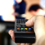 Person watching TV, pressing the remote control