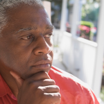 Older man looking thoughtfully, contemplatively into the distance from his porch