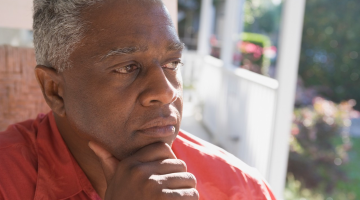 Older man looking thoughtfully, contemplatively into the distance from his porch