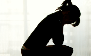 Silhouette of a person with their head in their hands, looking distraught