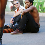 Two people sitting on the ground, catcalling someone walking by