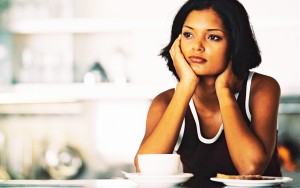 Person siting at a table with a tea cup, looking thoughtfully sad