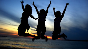 Silhouettes of three people jumping up in the air