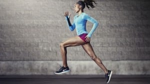 Fit person running, with a gray wall in the background