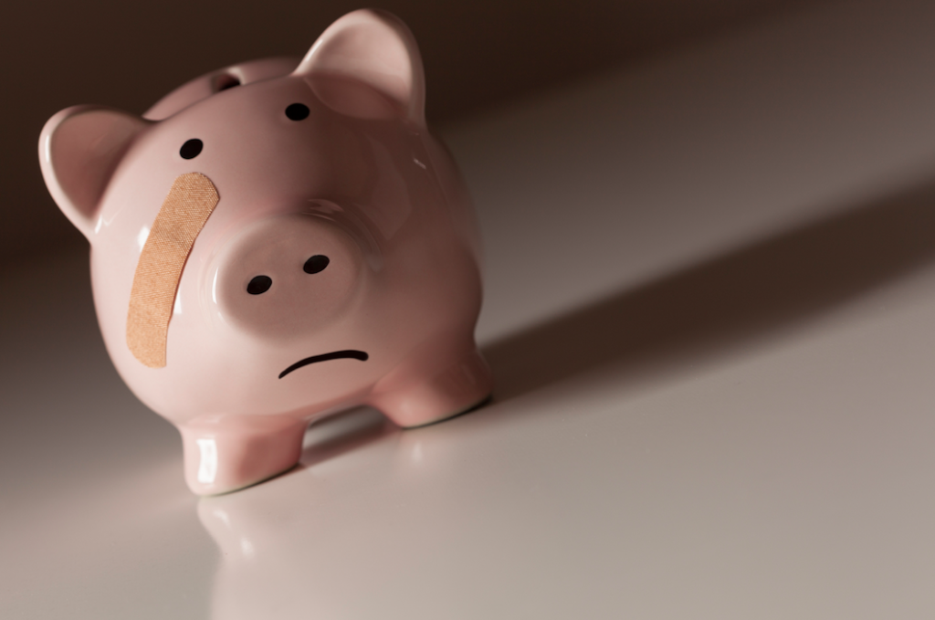 Piggy bank with a sad face and a bandaid on its face