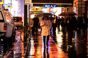 Person standing in the rain in Times Square, which is lit up all around them