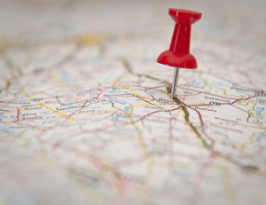 A road map is shown close up, with a red push pin stuck in a spot