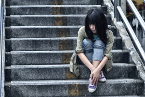 Sad looking young person, sitting on steps