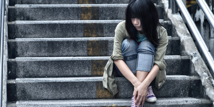 Sad looking young person, sitting on steps